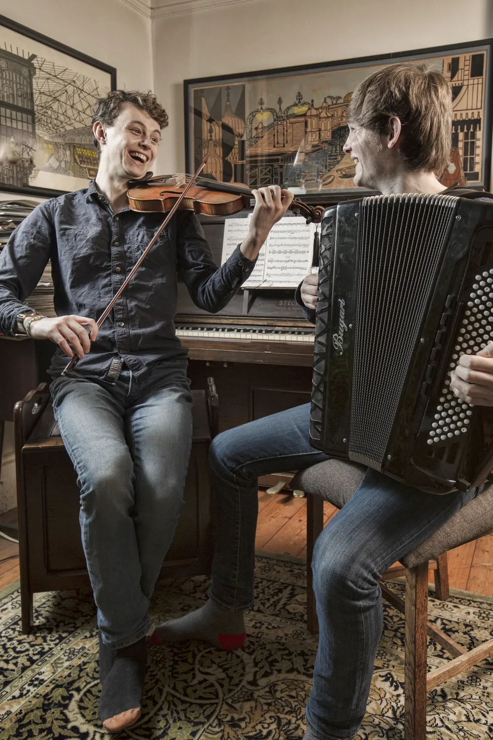 Roo and Neil seated beside an upright piano