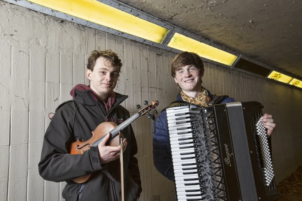 Roo and Neil with fiddle and accordion under a strip light