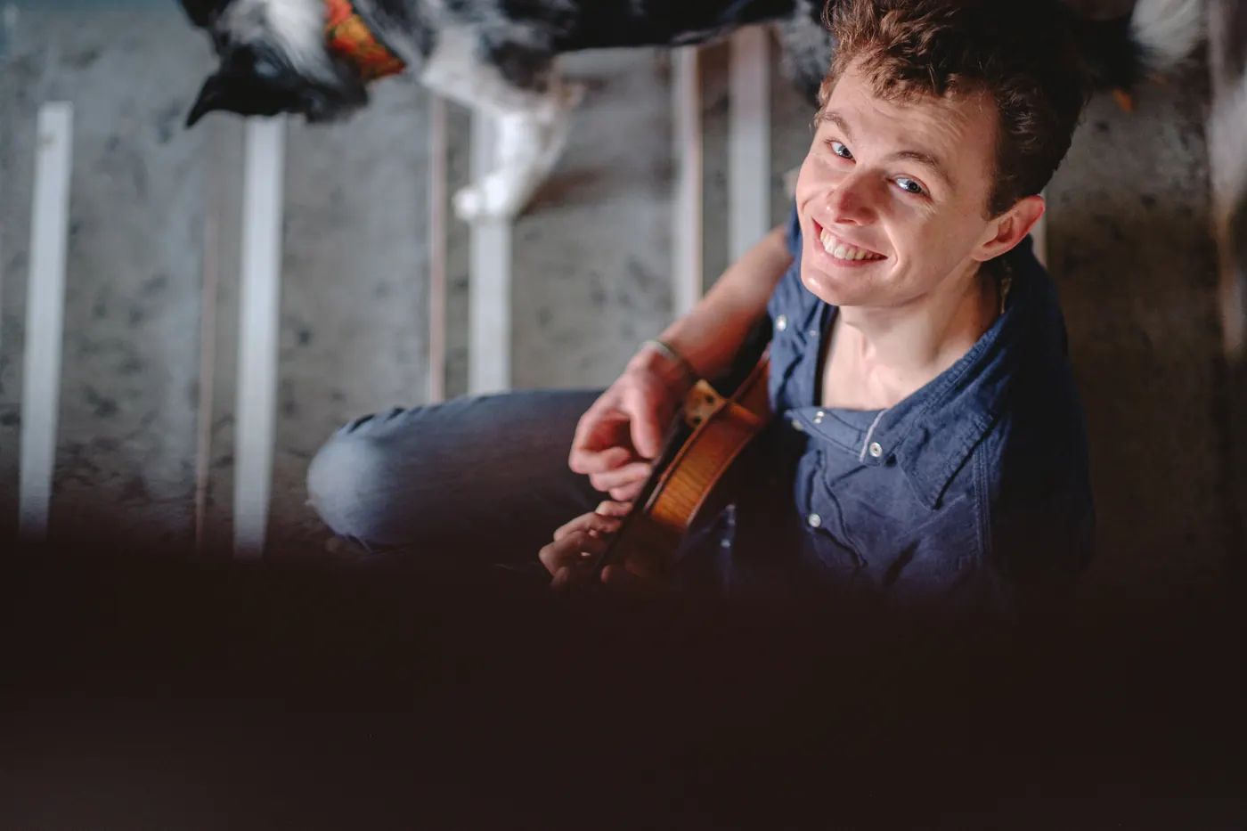 Roo smiling up at the camera while holding his fiddle